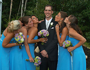 A wedding party candid of bridesmaids fawning over groom.